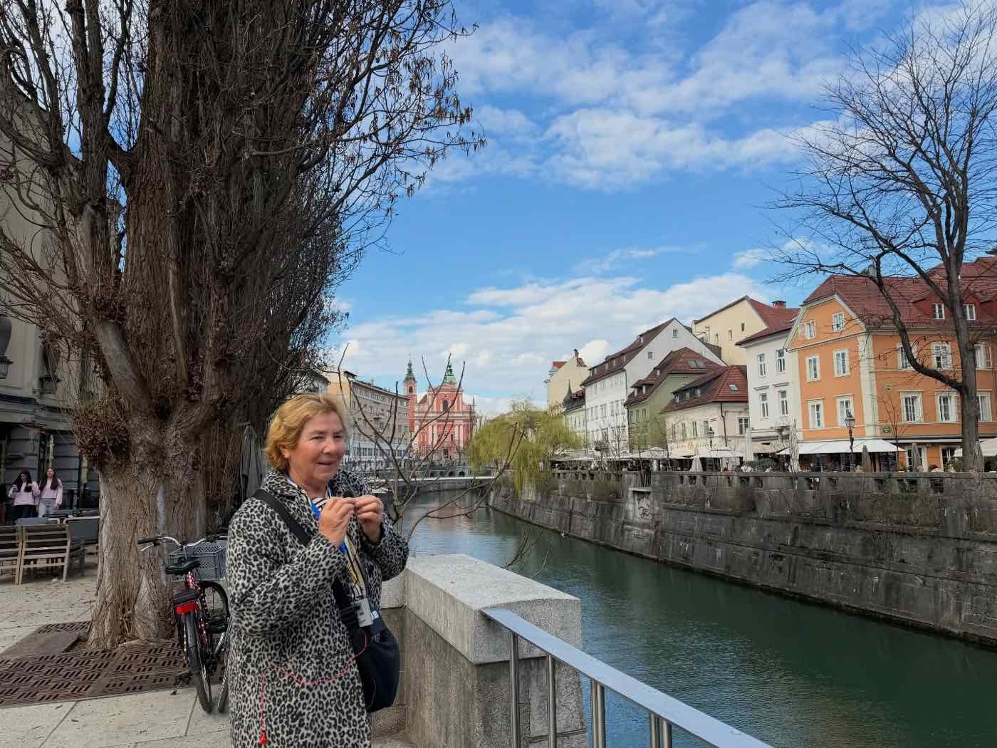Vodnica z naglavnim mikrofonom vodi ogled ob Ljubljanici, v ozadju Frančiškanska cerkev
